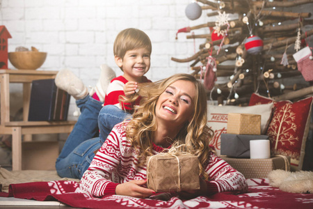 幸福的母亲和儿子的肖像在圣诞树的背景下, 在新年的房间。明信片的想法