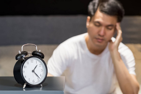 亚洲男子坐在床上失眠和睡眠紊乱思考他的问题在晚上