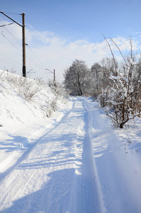 一条平行于铁路线的路在大雪后的晴天被雪覆盖着。