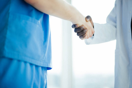 密切的医疗握手。博士会议。两位自信的医生站在医院里, 讨论病人并握手。