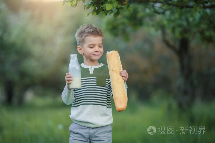 小男孩在花园里喝牛奶和吃面包