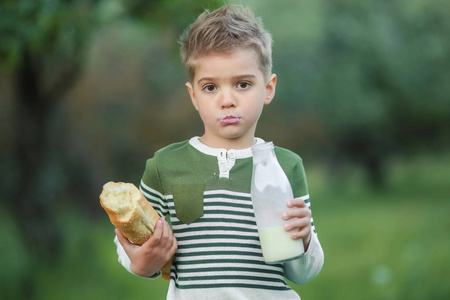 小男孩在花园里喝牛奶和吃面包