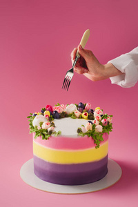 妇女用叉子和甜蛋糕装饰与花被隔绝粉红色的镜头