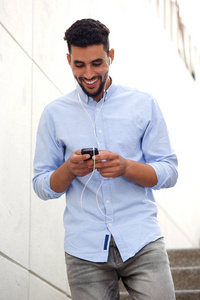 年轻男子的肖像微笑和步行手机和耳机