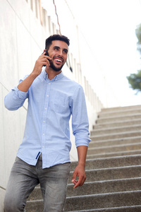 微笑的北非男子的肖像走路和说话的手机