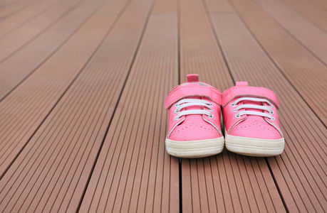 双粉红色婴儿皮鞋在木板背景图片