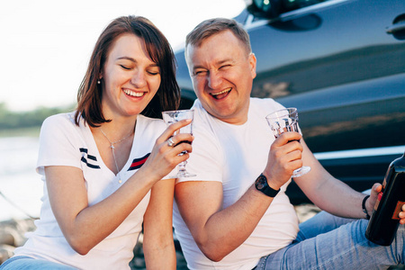 幸福的年轻夫妇在 roadtrip 的肖像。男人和女人坐在格子上户外野餐概念