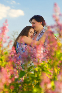 快乐的年轻夫妇在花园中的花