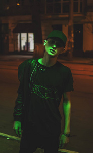 年轻人在一顶帽子摆在夜间在绿色照明