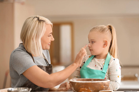 小女孩和她的祖母在厨房吃面粉乐趣