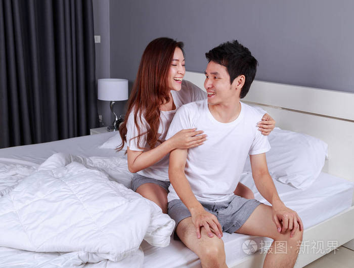 快乐的年轻迷人的情侣拥抱在床上卧室