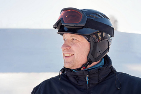 滑雪头盔和滑雪护目镜的人的侧面画像在滑雪滑雪板下降的背景从山