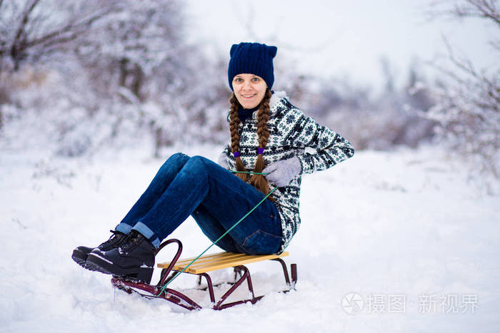 快乐的年轻女子在雪地里玩雪橇