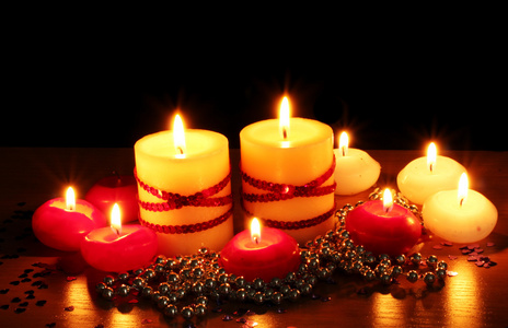 美丽的蜡烛和黑色背景上的木桌上的装饰