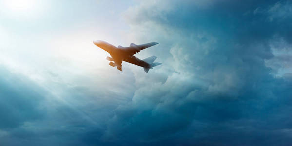 商业飞机飞行在黑暗的天空和云彩在日出