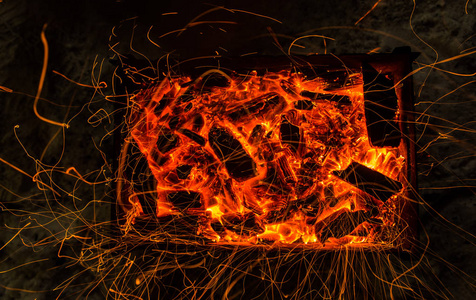 明亮的橙色火花从篝火上长期暴露和燃烧的煤。动态线跟踪