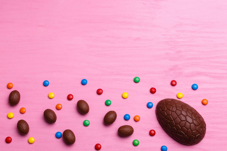 巧克力复活节彩蛋和五颜六色的糖果在一个明亮的粉红色背景。复活节甜蜜的概念