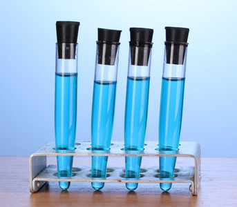 蓝色背景上的木桌上的蓝色液体的试管