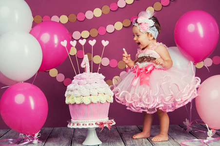 一个小快乐的生日女孩的肖像与第一个蛋糕。吃第一块蛋糕粉碎蛋糕