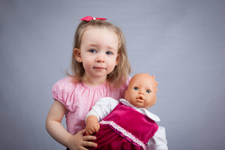 可爱的女孩的肖像与娃娃。灰色背景