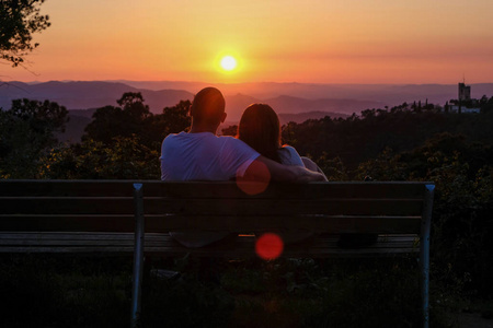 浪漫的情侣在山上的彩色日落背景