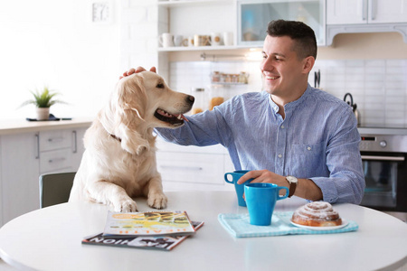 主人的肖像与他的友好的狗在家里吃早饭