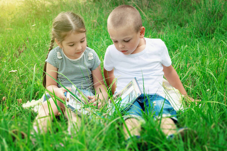 孩子们在阳光明媚的日子里坐在草地上看书。