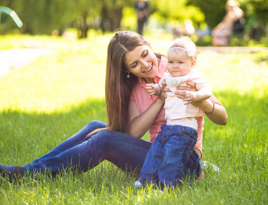 Youmg 幸福的女人和她可爱的小宝宝夏天阳光公园户外玩