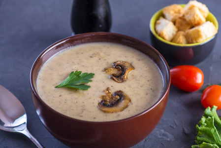 蘑菇奶油汤在桌子上的褐色盘子里。黑暗的背景。健康秋季素食传统菜肴