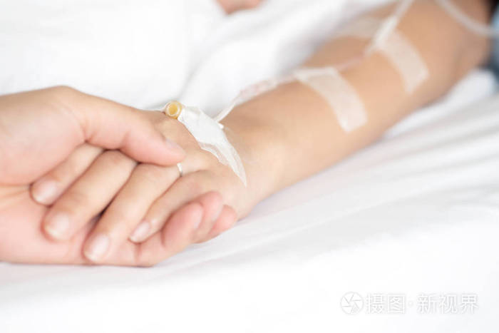 在医院病床上静脉注药治疗男性手牵手接受盐水溶液的选择重点安慰和