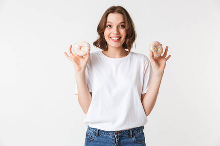 一个微笑的年轻女子的肖像持有两个甜甜甜圈孤立的白色背景