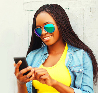 漂亮的微笑非洲妇女使用智能手机在城市