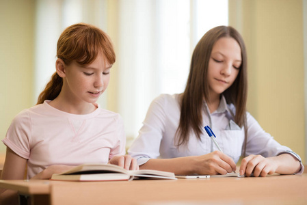 2学生女孩坐在桌旁