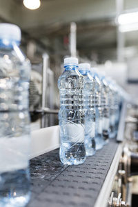 装瓶厂水灌装流水线, 用于加工和装入蓝色瓶子中的纯净泉水。选择性聚焦