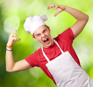 年轻厨师男人穿着围裙做侵略性 gestur 的肖像