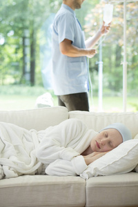 虚弱的妇女与乳腺癌睡在沙发上, 并支持她的照顾者