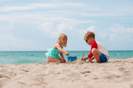 快乐的小男孩和女孩在沙滩上玩沙