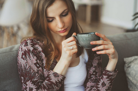 在家里独自坐着喝杯茶或咖啡的年轻体贴的女人的肖像。抑郁症与心理健康概念