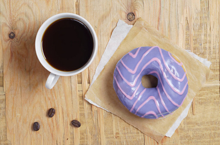 一杯咖啡和一个紫色釉的甜甜圈在老木背景上, 顶部视图