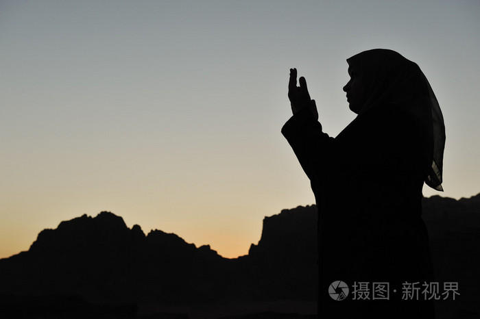 一名在沙漠上祈祷的穆斯林妇女的剪影
