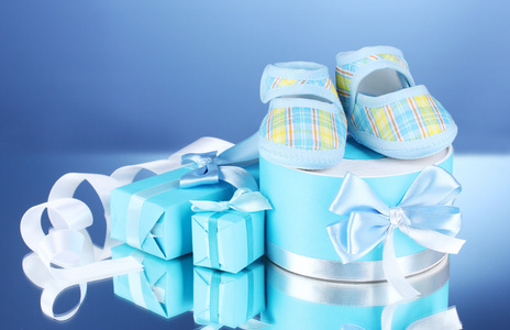 精美的礼物和在蓝色背景上的婴儿毛线鞋