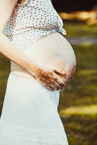 未来的妈妈抱着她的肚子涂上 mehendi