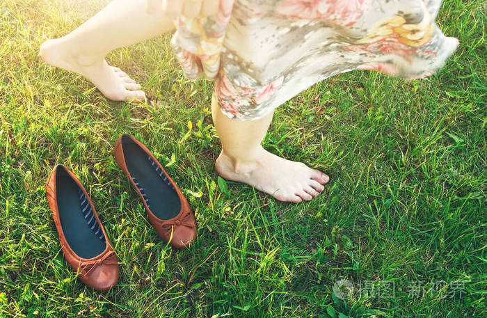 女孩赤脚走在绿色的草地上, 向下看视图