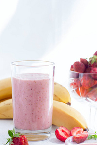 草莓和香蕉的冰沙在白色桌上的玻璃杯, 选择性聚焦