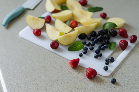 切片新鲜的苹果, 草莓, 蓝莓和黑莓, 薄荷叶周围, 新鲜的夏季水果, 厨房刀边