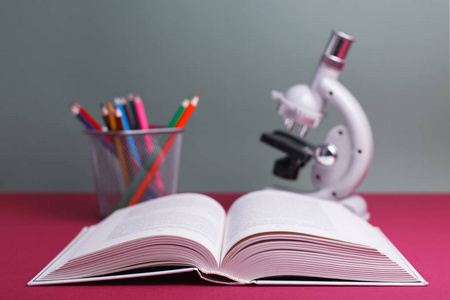 概念教育打开的书, 彩色铅笔和在 auditoriu 的书桌上的显微镜