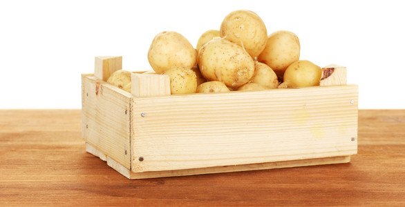 年轻土豆在一个木箱上白色背景特写的表格