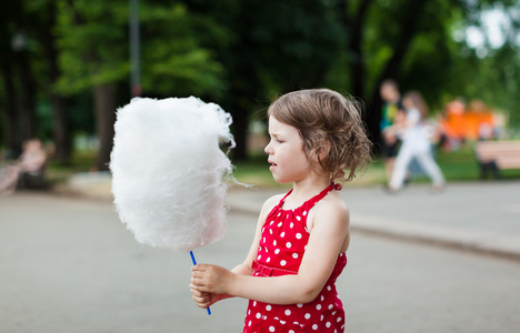 漂亮的小女孩在公园里吃棉花糖图片