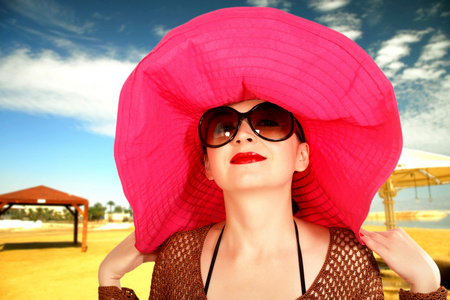 一个红色的帽子，大型眼镜在海滩上的女孩