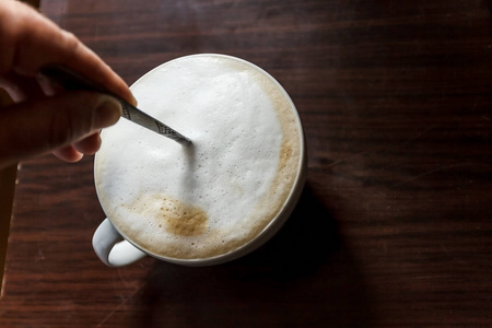 一杯咖啡与泡沫被人的手搅动